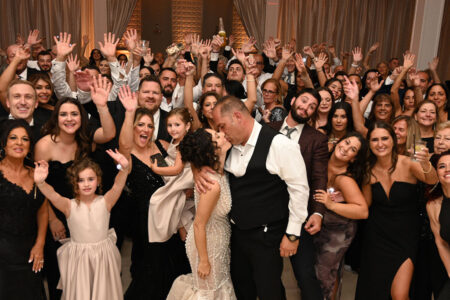 A joyful wedding celebration with the bride, groom, and guests posing happily.