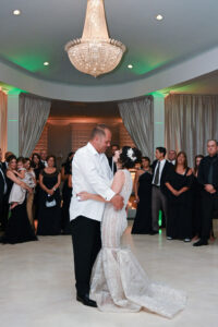 A couple shares their first dance at a wedding reception surrounded by guests.
