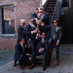 A group of men in suits celebrating with champagne outdoors.