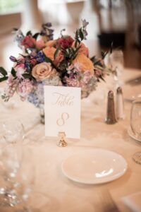 Elegant table centerpiece with flowers and a gold-accented table number 8 card.
