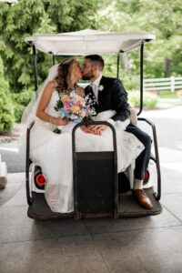 Bride and groom kissing on a golf cart during their wedding day.