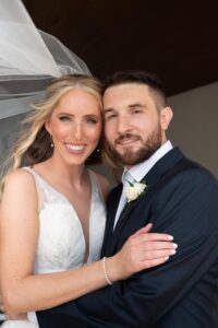 A happy couple on their wedding day, smiling at the camera.
