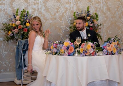 Bride and groom sitting at a decorated wedding table.