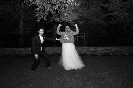 A bride and groom striking playful poses outdoors at night.