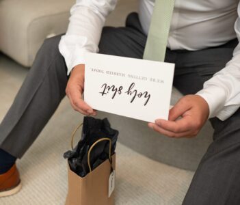 Person holding a card that says 'Enjoy Enjoy' with a gift bag nearby.