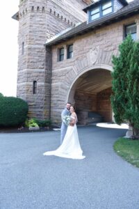 Bride in a white wedding dress standing outside a stone building entrance.