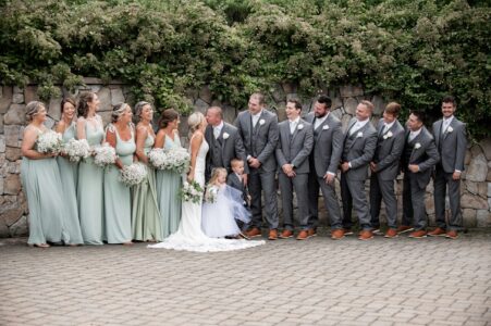 Bride and groom pose with their wedding party outdoors.