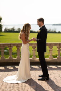 Bride and groom exchanging vows by a waterfront during sunset.