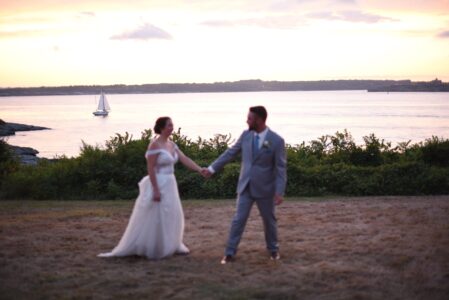 A couple holding hands by a lakeside at sunset.