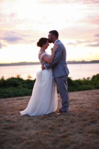 Bride and groom embracing at sunset on a beach.