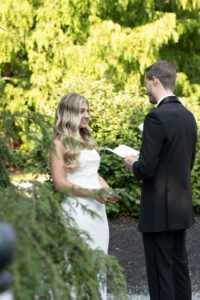 Bride and groom exchanging vows outdoors surrounded by greenery.