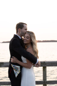Couple embracing tenderly by the water at sunset.