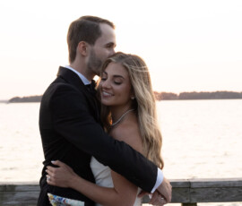 Couple embracing tenderly by the water at sunset.