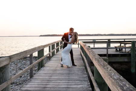 Couple sharing a romantic dance on a wooden pier at sunset.